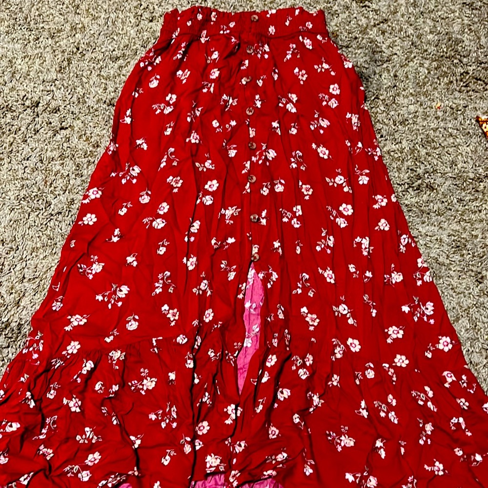red skirt with white flowers. has brown buttons down the front and a slit.